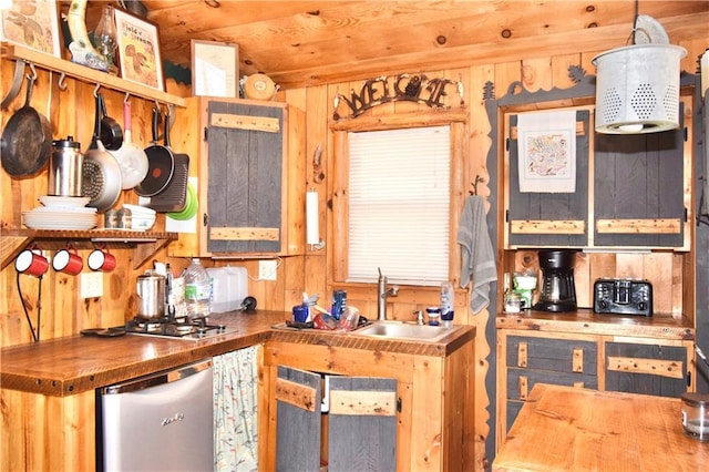 kitchen with stainless steel dishwasher, a sink, butcher block countertops, and wood walls