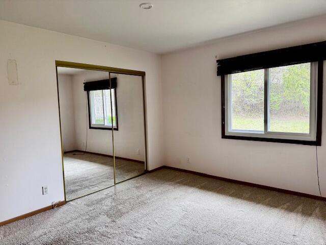 unfurnished bedroom with a closet, carpet flooring, and baseboards