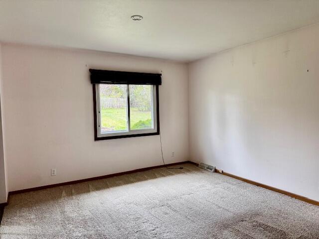 carpeted empty room featuring baseboards