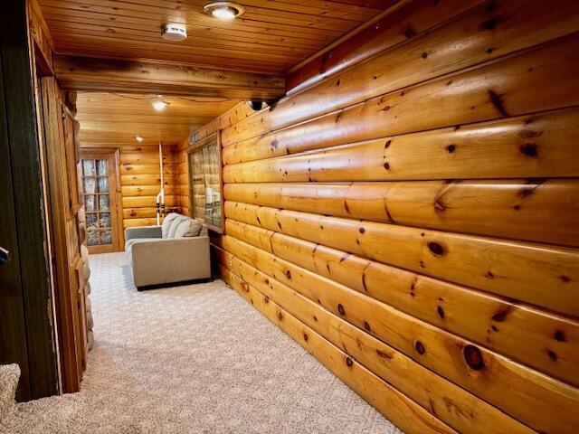 hall with log walls, wood ceiling, and carpet