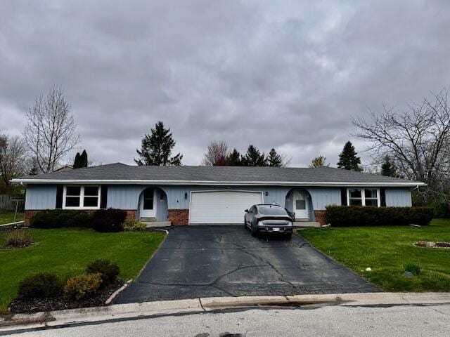 view of front of property featuring a garage, a front yard, brick siding, and aphalt driveway