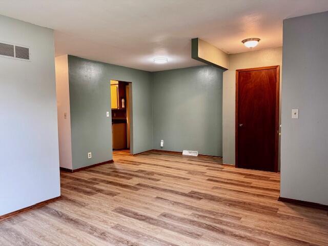 empty room with baseboards, visible vents, and light wood-type flooring