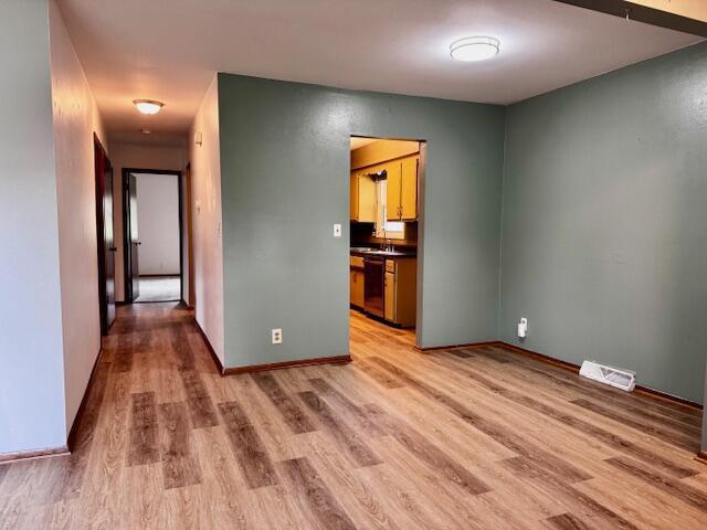 interior space with baseboards, visible vents, a sink, and light wood-type flooring