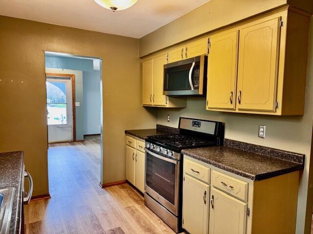 kitchen featuring light wood-style floors, appliances with stainless steel finishes, and dark countertops