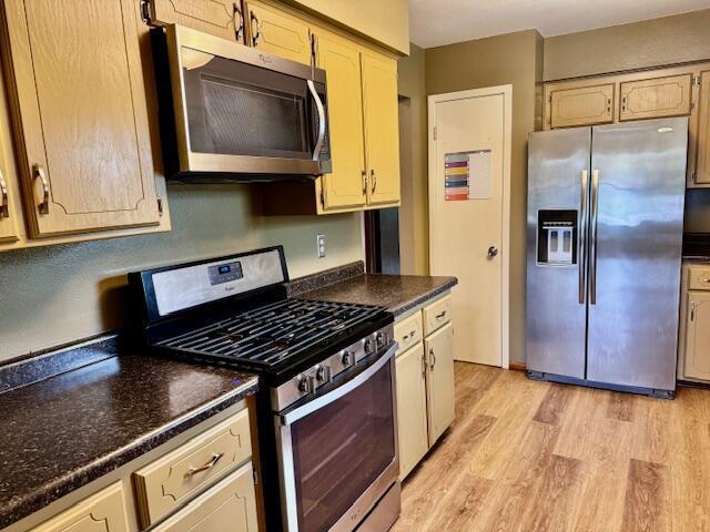 kitchen featuring light wood finished floors, appliances with stainless steel finishes, and dark countertops