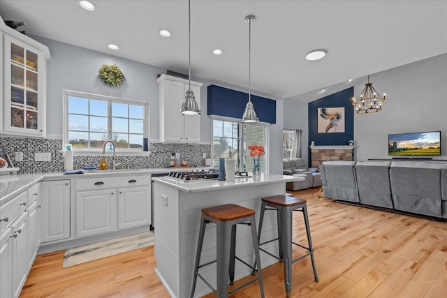 630 Polaris St, West Bend, WI 53095 - kitchen featuring a kitchen island, backsplash, a sink, and light wood-style floors