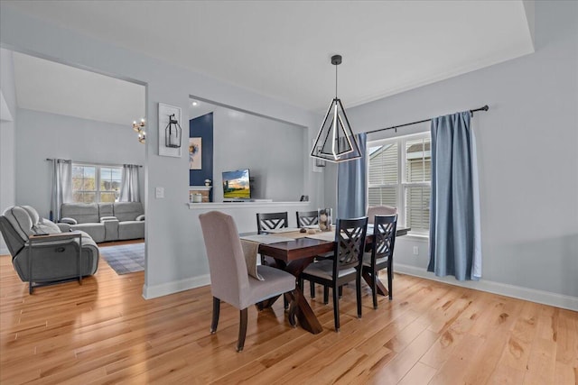 630 Polaris St, West Bend, WI 53095 - dining area with light wood-style floors, baseboards, and a chandelier
