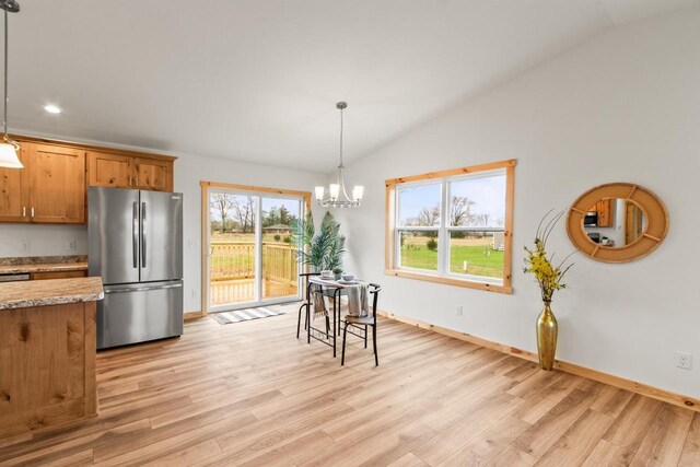 dining area featuring light wood-style floors, baseboards, lofted ceiling, and a chandelier