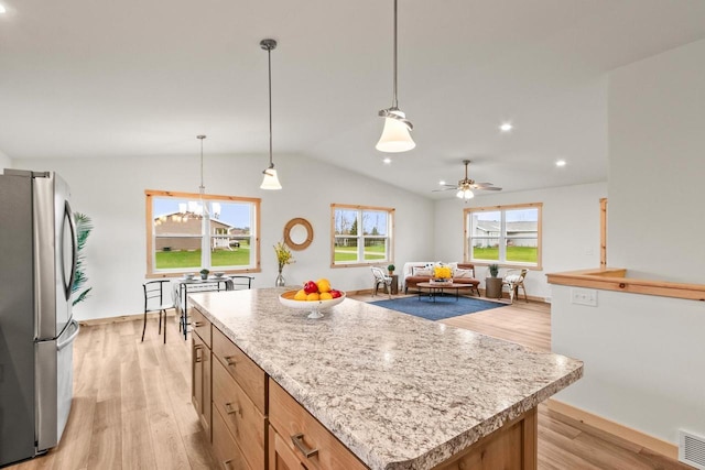 kitchen featuring freestanding refrigerator, lofted ceiling, a center island, light wood finished floors, and ceiling fan with notable chandelier