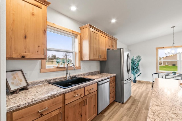 kitchen with appliances with stainless steel finishes, a sink, light wood-style flooring, a wealth of natural light, and vaulted ceiling