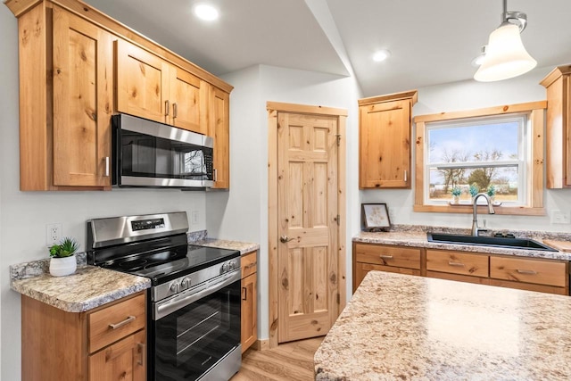 kitchen with appliances with stainless steel finishes, a sink, light wood-style flooring, recessed lighting, and pendant lighting