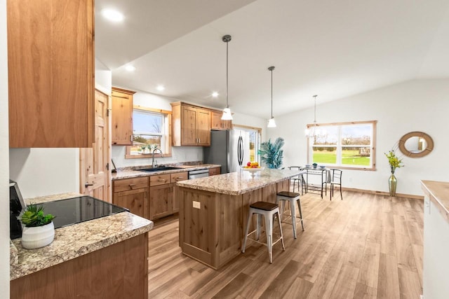 kitchen with appliances with stainless steel finishes, a center island, a sink, a breakfast bar, and light wood-style flooring