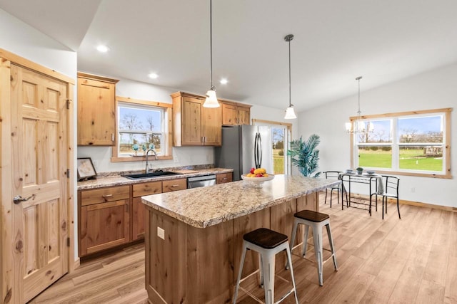 kitchen featuring a kitchen breakfast bar, light wood-type flooring, a center island, a sink, and appliances with stainless steel finishes