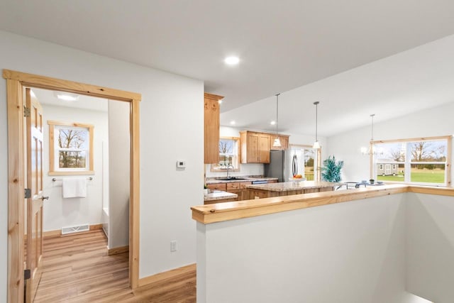 kitchen with visible vents, a sink, light countertops, freestanding refrigerator, and light wood finished floors