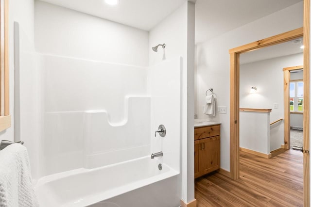 full bathroom with baseboards,  shower combination, wood finished floors, and vanity