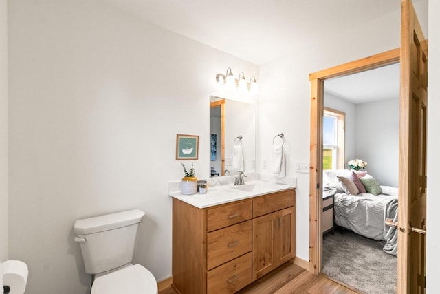 ensuite bathroom featuring vanity, connected bathroom, wood finished floors, and toilet