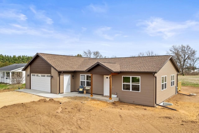 single story home with a shingled roof, dirt driveway, and an attached garage