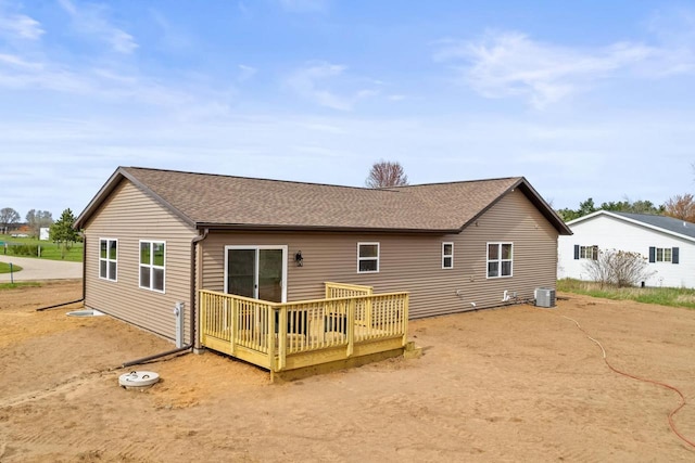 back of property with roof with shingles, a wooden deck, and cooling unit