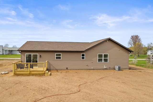back of property with central AC unit, roof with shingles, and a wooden deck