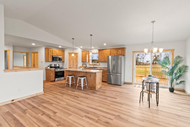 kitchen with appliances with stainless steel finishes, a sink, lofted ceiling, and light wood-style floors