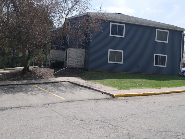 view of side of property with a lawn and uncovered parking