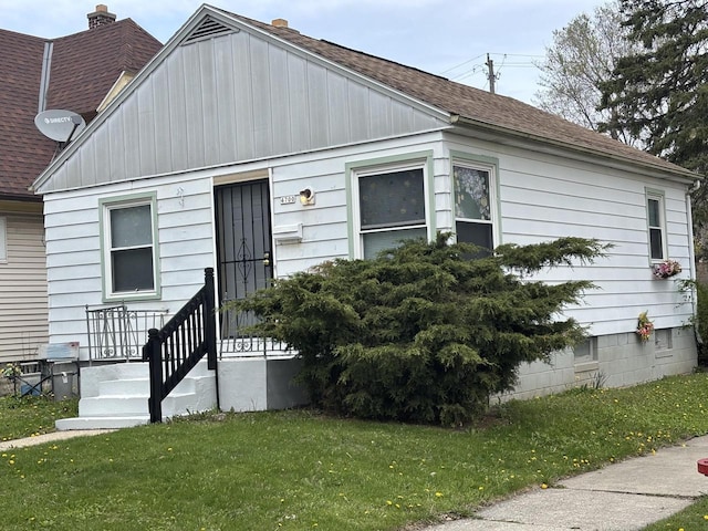 bungalow-style home with roof with shingles and a front yard