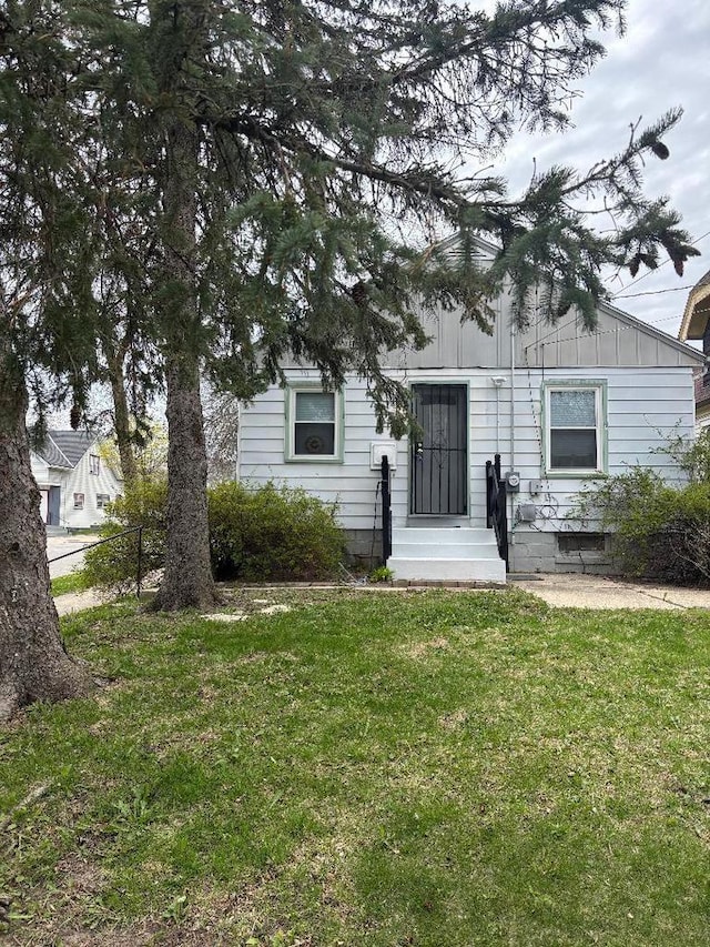 obstructed view of property featuring fence, board and batten siding, and a front lawn