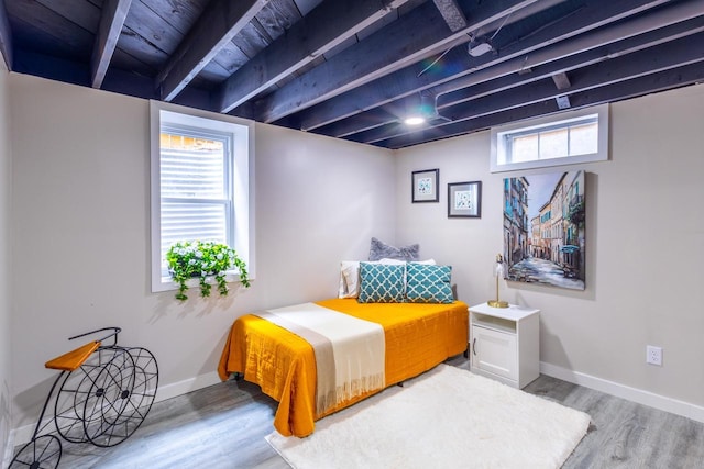 bedroom with baseboards, wood finished floors, and multiple windows