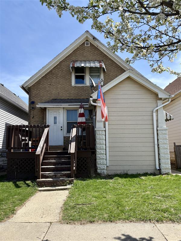 view of front of property with brick siding, a front lawn, and a deck