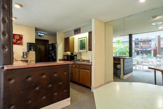 kitchen featuring light colored carpet, light countertops, a textured ceiling, and freestanding refrigerator