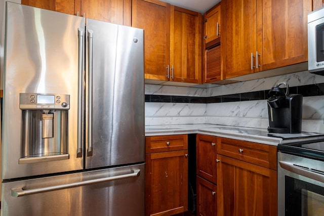 kitchen with brown cabinetry, light countertops, backsplash, and stainless steel appliances
