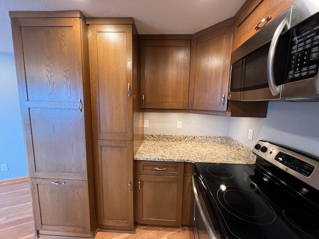 kitchen featuring light stone counters, light wood finished floors, and stainless steel appliances