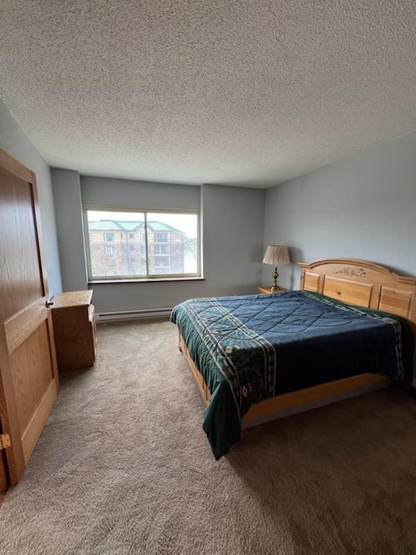 carpeted bedroom with a baseboard radiator and a textured ceiling