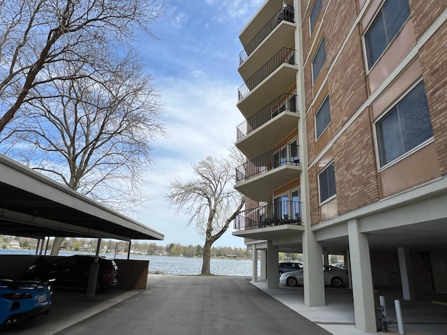 view of building exterior featuring a water view and covered parking