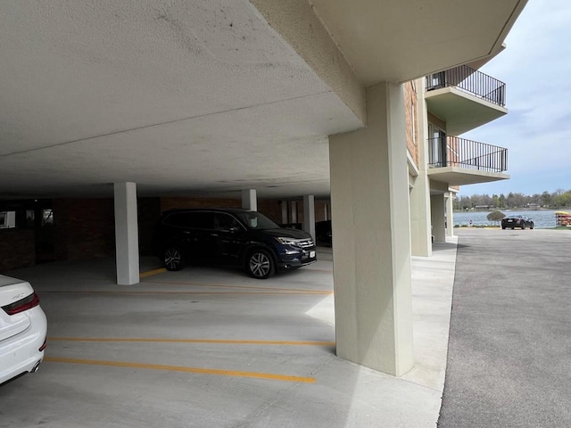 view of vehicle parking featuring a parking deck and a water view