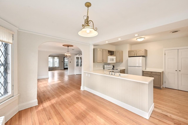kitchen with hanging light fixtures, white appliances, arched walkways, light countertops, and light wood-type flooring