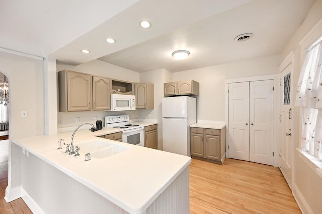 kitchen with a sink, light wood finished floors, white appliances, light countertops, and visible vents