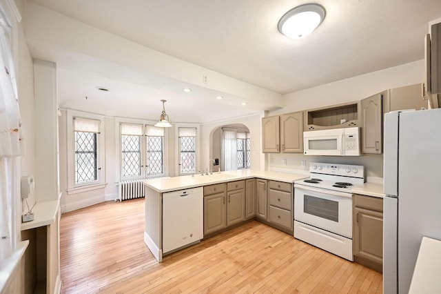 kitchen with radiator, a peninsula, white appliances, plenty of natural light, and arched walkways