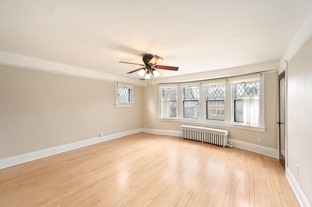 spare room with baseboards, a ceiling fan, radiator, and light wood-style flooring