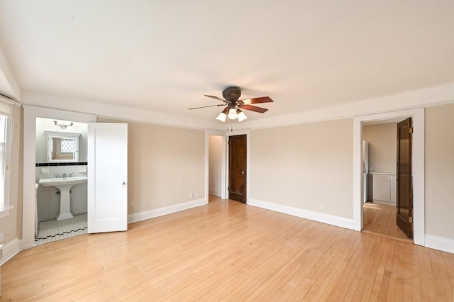 unfurnished bedroom with baseboards, ensuite bathroom, and light wood-style floors