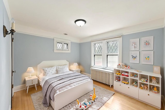 bedroom featuring radiator heating unit, baseboards, and hardwood / wood-style floors