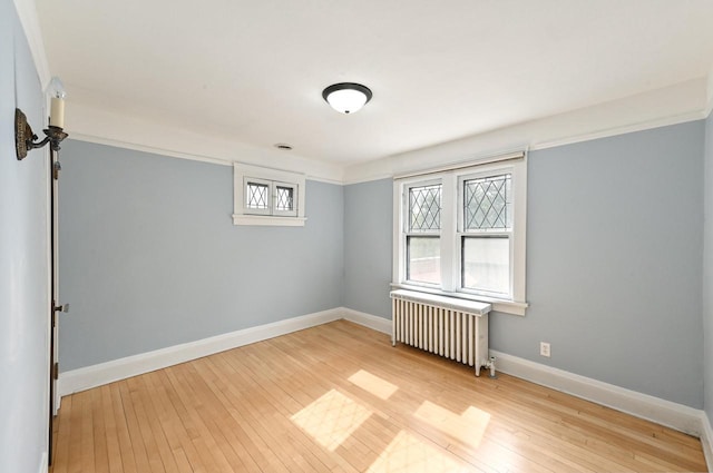 unfurnished room featuring radiator, baseboards, and hardwood / wood-style flooring