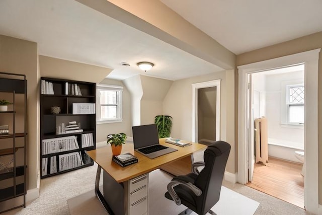office area featuring baseboards, radiator heating unit, vaulted ceiling, and light carpet
