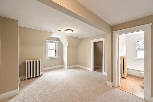 bonus room with baseboards, light carpet, and radiator heating unit