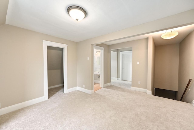 spare room featuring light colored carpet and baseboards