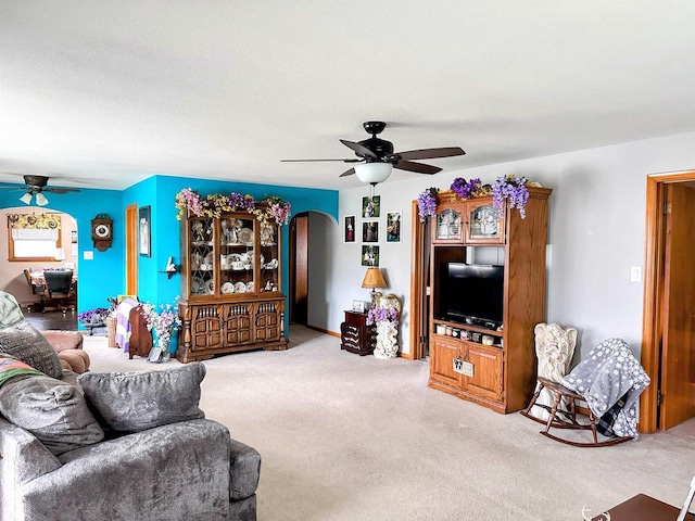 living room with carpet floors, a ceiling fan, and arched walkways