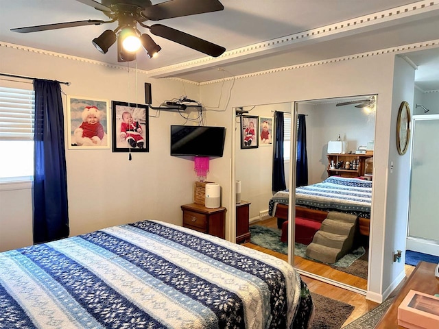 bedroom featuring a closet, a ceiling fan, baseboards, and wood finished floors