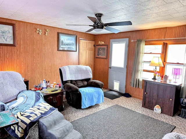 carpeted living area with wooden walls and a ceiling fan
