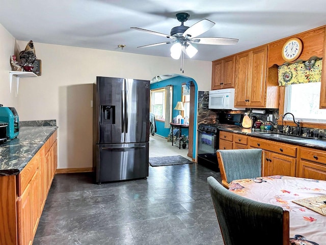 kitchen with a ceiling fan, stainless steel refrigerator with ice dispenser, gas stove, a sink, and white microwave
