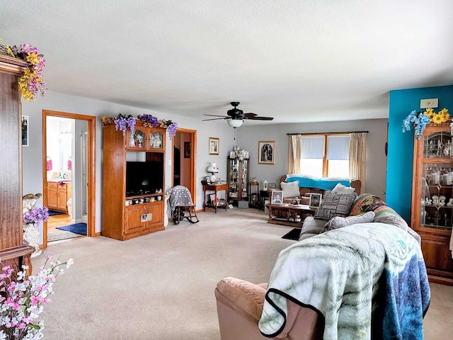 living room with a ceiling fan, a textured ceiling, and light colored carpet